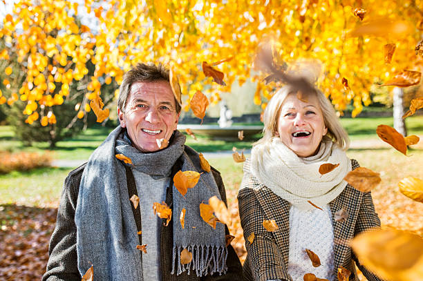 istock Active senior couple in autumn park throwing leaves 597965118