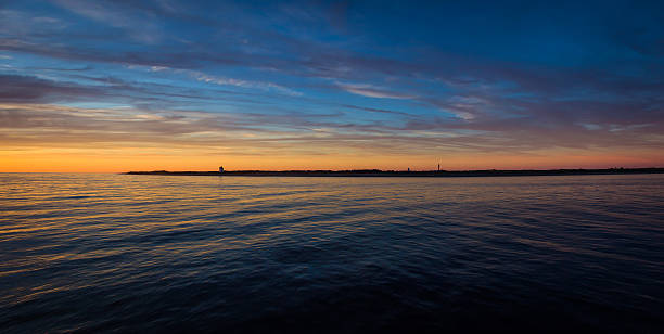 istock Sunset with a silhouette of a small lighthouse from sea 597965386