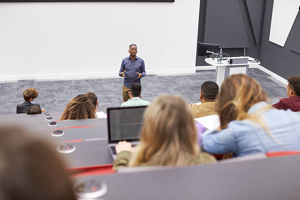 istock Man lectures students in lecture theatre, back row seat POV 597967560