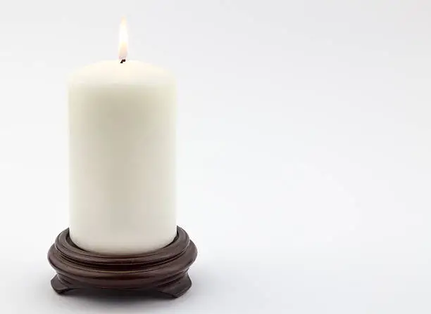 Photo of Single white lit candle on white background