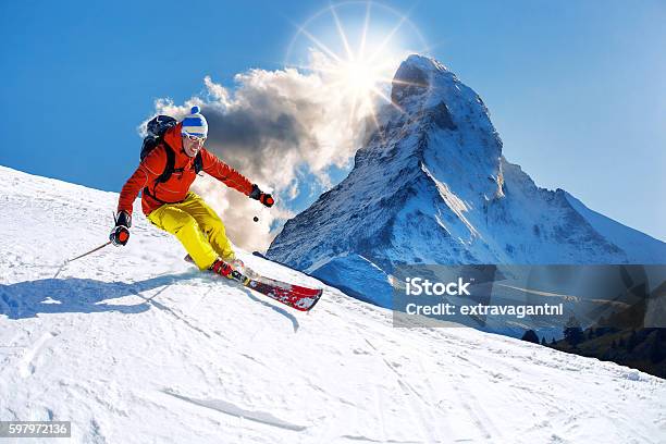 Skier Skiing Downhill Against Matterhorn Peak In Switzerland Stock Photo - Download Image Now