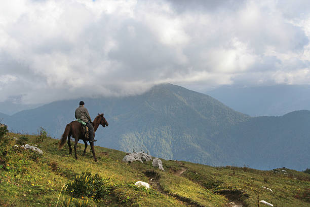 Horseman ride on top of mountains looks forward in blue sky. Adventures in wild nature