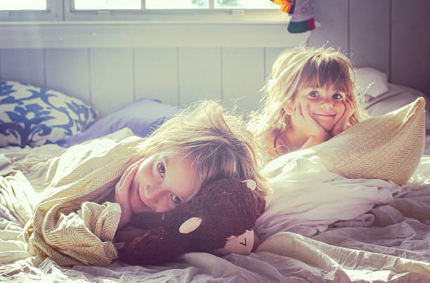 Cropped portrait of two adorable young kids lying in their blanket fort at home