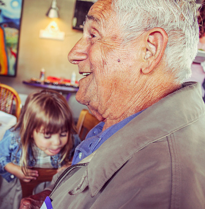 LIttle girl in the background sticks out her tounge, older gentleman smiles