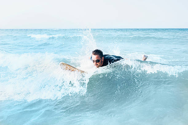 istock Young man lying on surfboard in the sea 598054816