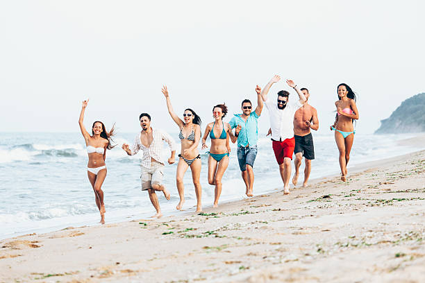 gruppo di giovani felici che corrono in spiaggia - men beach running shirtless foto e immagini stock