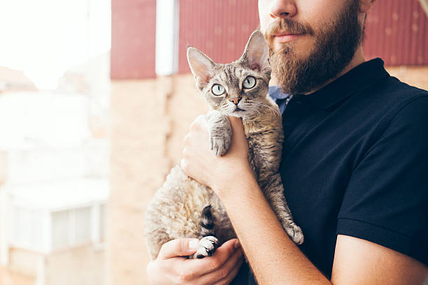 istock Beautiful man is holding and hugging cute Devon Rex cat 598055692