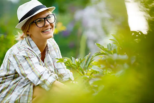 blonde woman in hat on background of plants