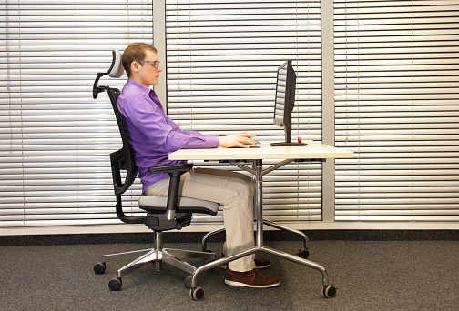 correct sitting position at workstation. man on chair working with computer