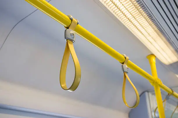 Yellow hand grip straps inside subway train, selective focus on front object