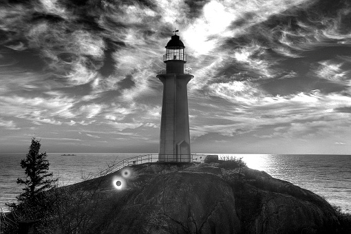Black and white lighthouse with a cloudy sky in the background