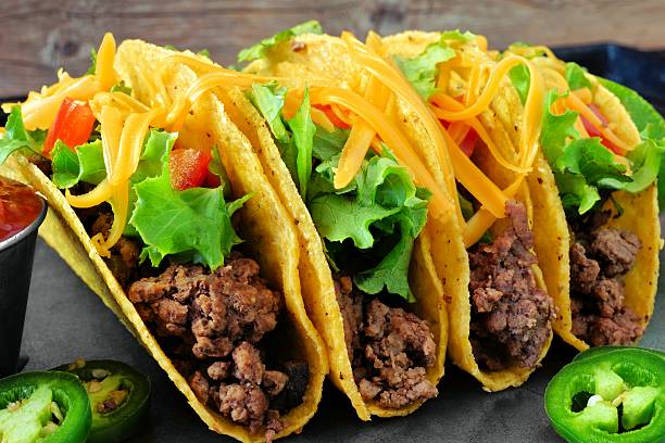 Group of ground beef hard shelled tacos close up Group of hard shelled tacos with ground beef, lettuce, tomatoes and cheese close up shredded photos stock pictures, royalty-free photos & images