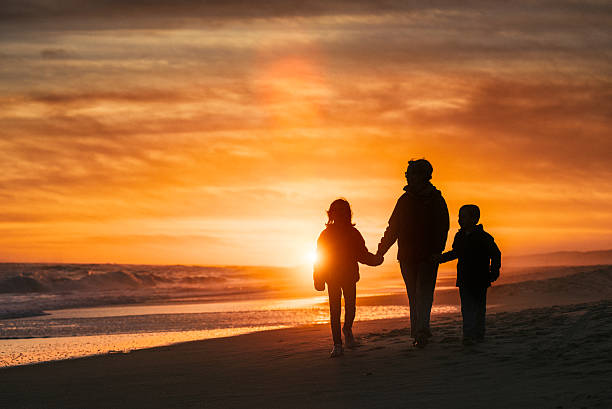 Family walk by the beach at sunset