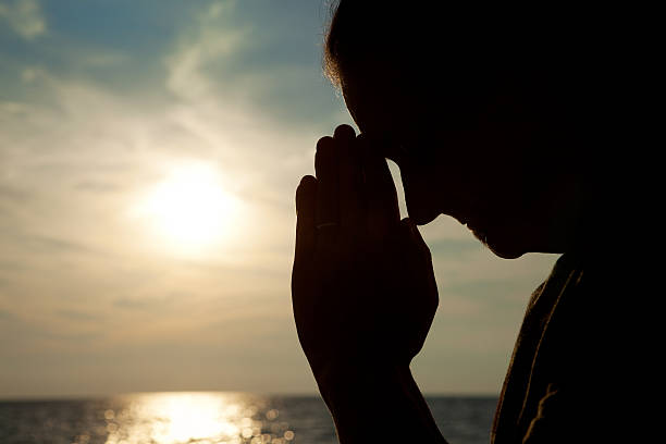 istock Silhouette Of Man Praying By Sunset 598068416