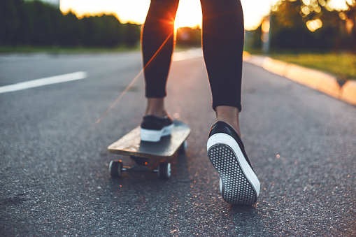 skateboarding woman legs at sunrise street