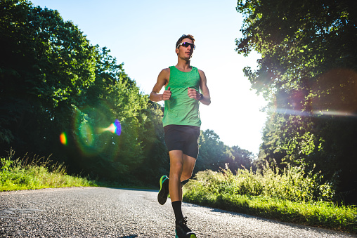 Male athlete running in the park on a sunny day.