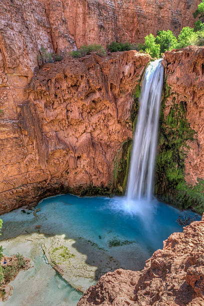 Mooney Falls Amphitheater Mooney Falls plunges into a deep blue-green pool surrounded by red travertine cliffs on the Havasupai Indian Reservation in the Grand Canyon. havasu creek stock pictures, royalty-free photos & images