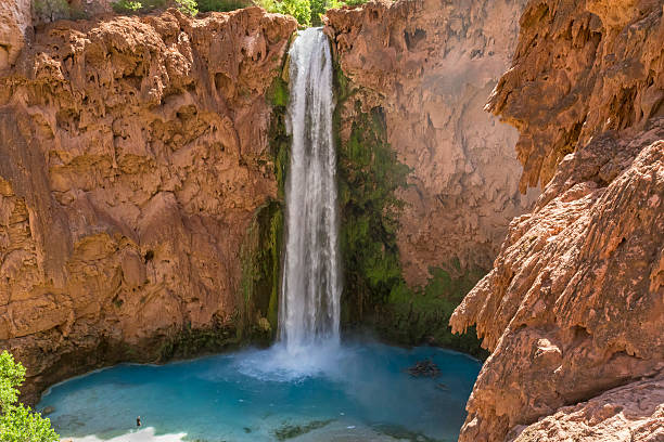 Mooney Falls and Travertine Cliffs Mooney Falls plunges into a deep blue-green pool surrounded by red travertine cliffs on the Havasupai Indian Reservation in the Grand Canyon. harasu canyon stock pictures, royalty-free photos & images