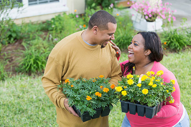 jeune couple noir à l’extérieur de la maison plantant des fleurs - heavy plant photos et images de collection