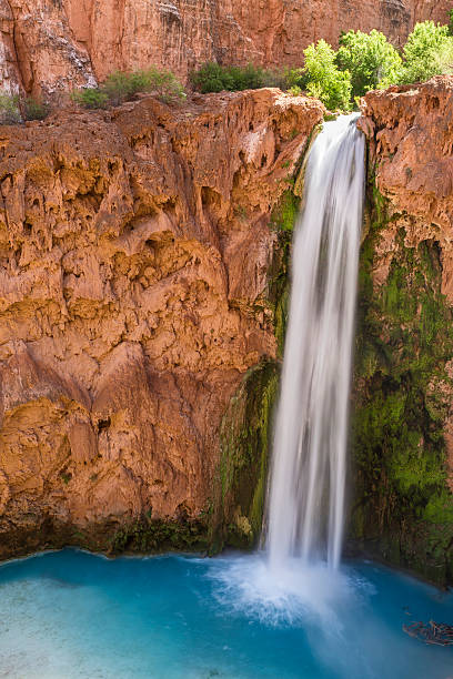 Silky Mooney Falls Mooney Falls plunges into a deep blue-green pool surrounded by red travertine cliffs on the Havasupai Indian Reservation in the Grand Canyon. harasu canyon stock pictures, royalty-free photos & images