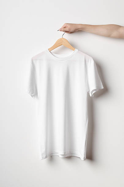 Men's Crew Neck T-Shirt Mock-Up Men's Crew Neck T-Shirt Mock-Up - Man holding a white t-shirt on a wooden clothes hanger round neckline stock pictures, royalty-free photos & images