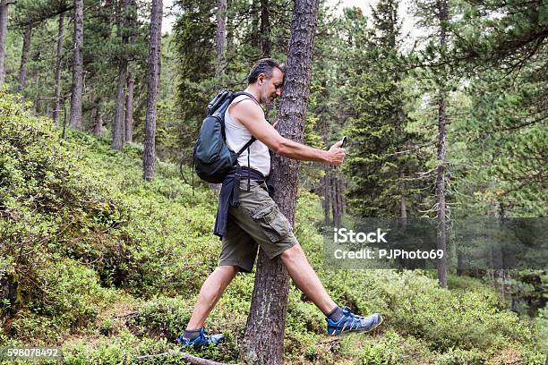 Man Beats Against Tree Playing Pokemongo On His Smart Phone Stock Photo - Download Image Now