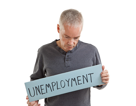 Sad man holding a sign saying Unemployment, isolated on a white background.