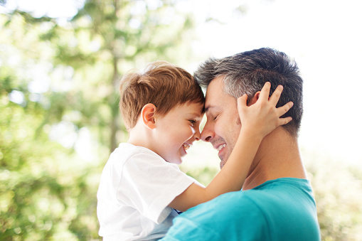 Father and son hugging outdoors, shallow depth of field