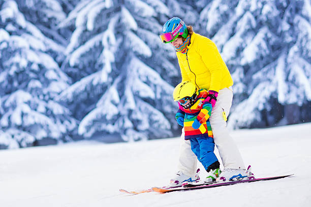 aktive mutter und kleiner junge lernen skifahren - skiurlaub stock-fotos und bilder