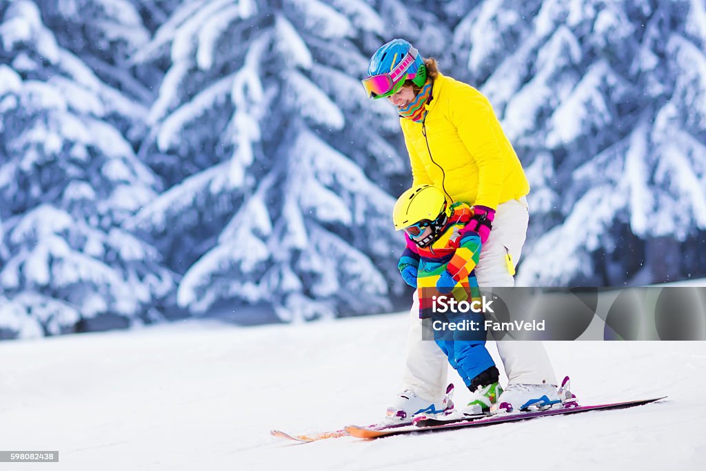 Active mother and little boy learning to ski Mother and little child skiing in Alps mountains. Active mom and toddler kid with safety helmet, goggles and poles. Ski lesson for young children. Winter sport for family. Little skier racing in snow Skiing Stock Photo