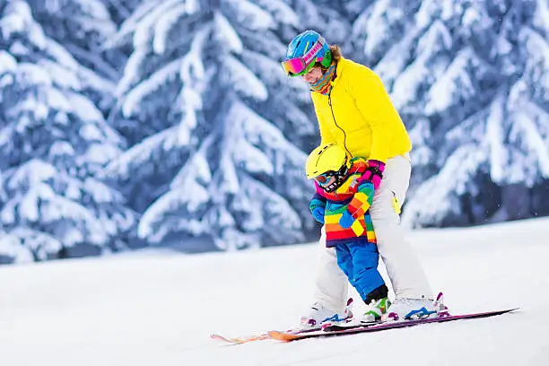 Photo of Active mother and little boy learning to ski