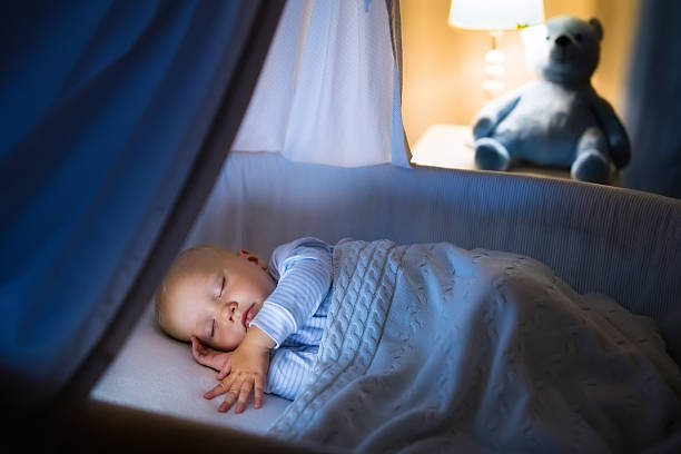 istock Baby boy sleeping in blue bassinet at night 598083184