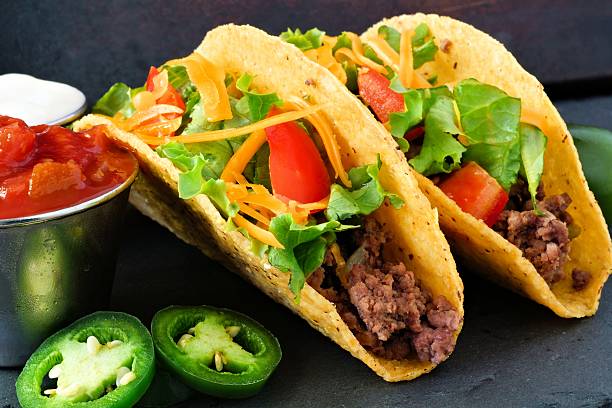 Hard shelled tacos with beef, lettuce, tomatoes and cheese close-up