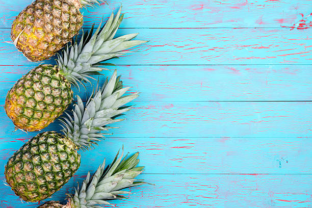 istock Slanted pineapples arranged on wooden table 598085956
