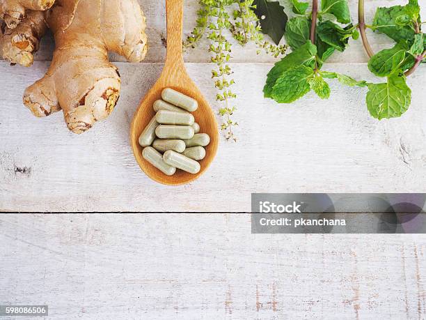 Foto de Pílulas De Ervas Em Colher De Pau E Erva Verde e mais fotos de stock de Suplemento nutricional - Suplemento nutricional, Gengibre - Especiaria, Natureza