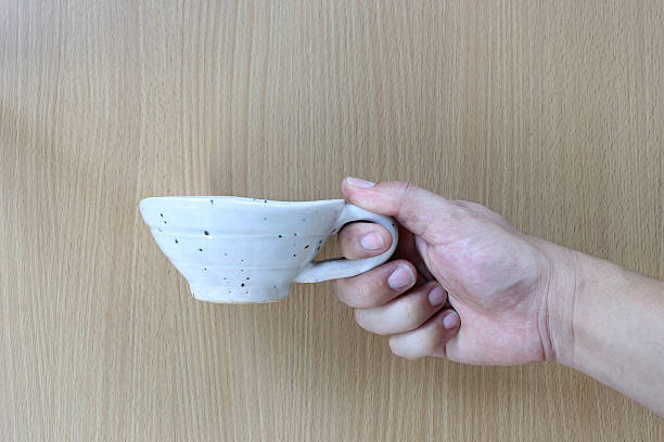 istock White cup in hand on wood background. 598097524