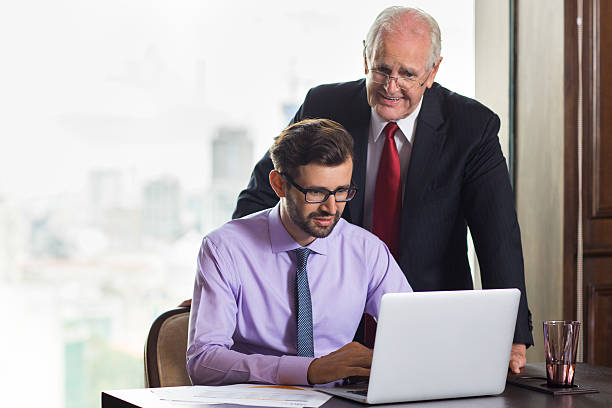 istock Senior boss consulting young subordinate working at laptop 598097968