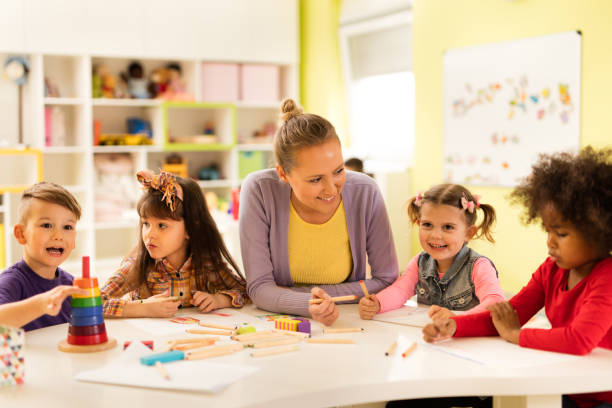 istock Happy preschool teacher having fun with kids during arts class. 598098624
