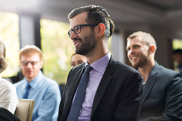 istock Smiling young businessman sitting at seminar with his colleagues 598098962