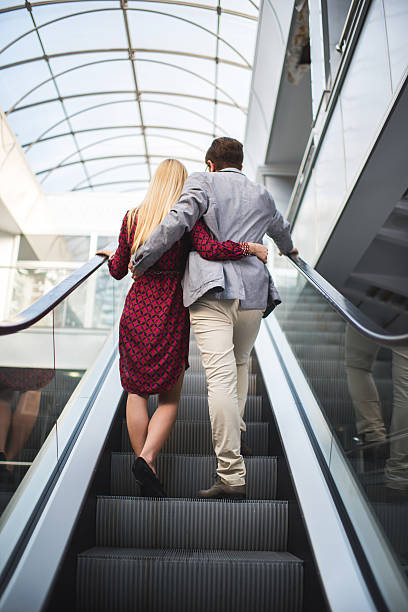 istock Rear view of embraced business couple on escalator. 598129914