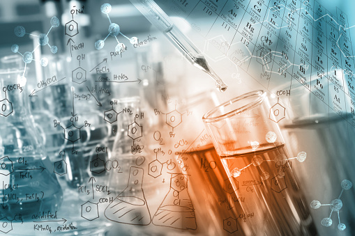 researcher dropping the clear reagent into test tube with periodic table and chemical equations background, for reaction testing in chemical laboratory.