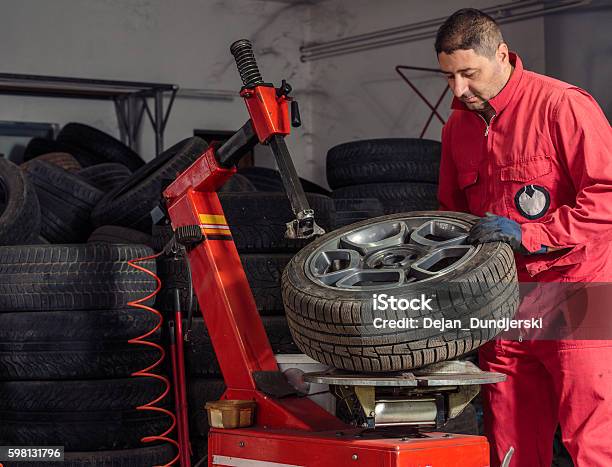 Mechanic Replacing A Tire On The Wheel Stock Photo - Download Image Now - Adult, Adults Only, Auto Repair Shop