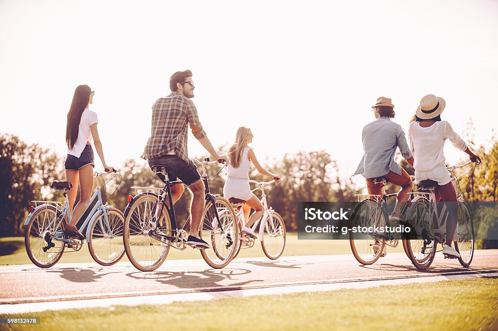Just a road ahead. Group of young cheerful people riding bicycles along a road Cycling Stock Photo