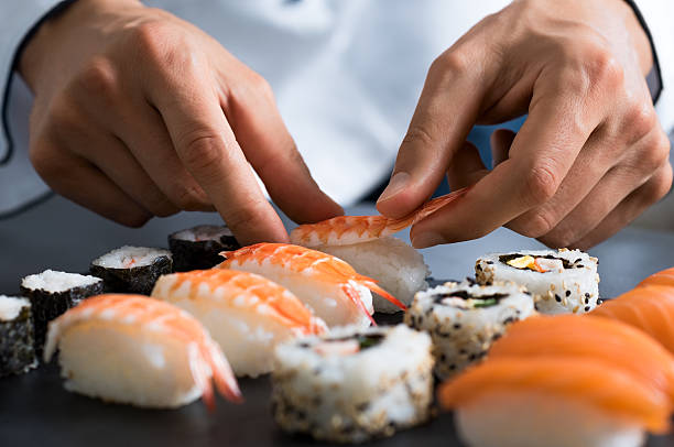 Chef preparing sushi Closeup of chef hands preparing japanese food. Japanese chef making sushi at restaurant. Young chef serving traditional japanese sushi served on a black stone plate. shrimp seafood photos stock pictures, royalty-free photos & images