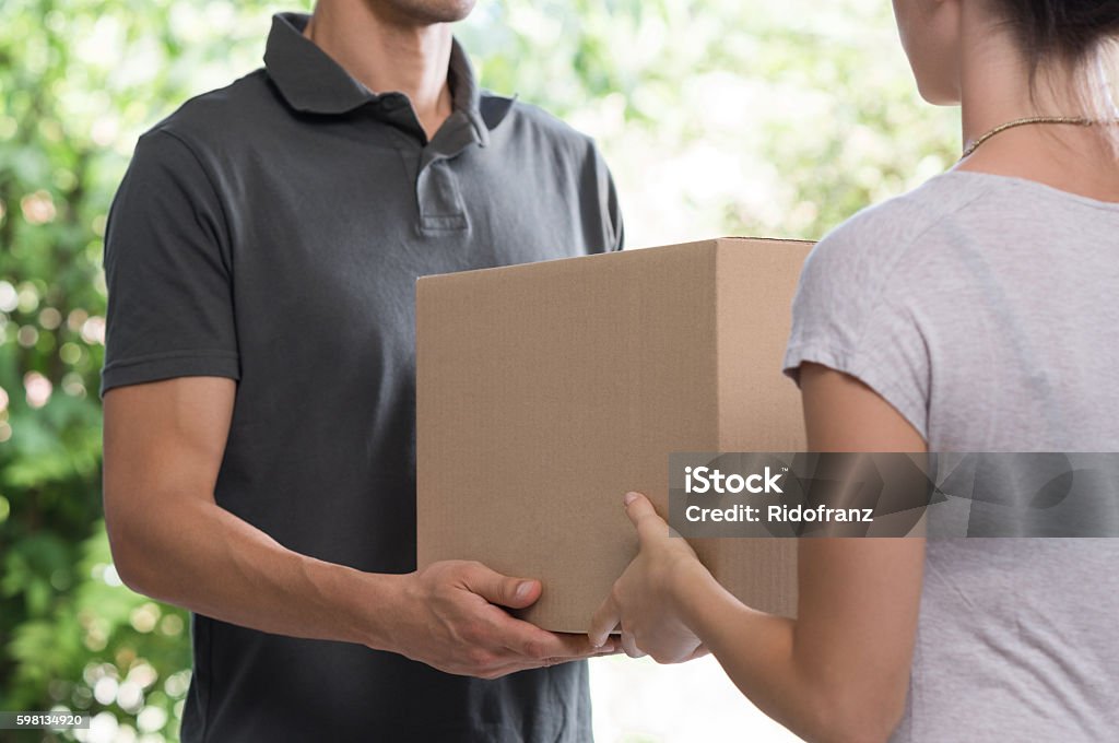 Courier delivering package Woman and courier during order transfer. Woman accepting delivery from deliveryman. Cropped image of delivery service worker giving parcel to client. Box - Container Stock Photo