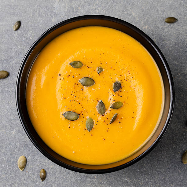 istock Pumpkin cream soup with pumpkin seeds in a black bowl 598136730