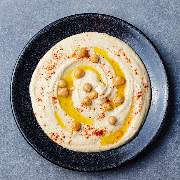 istock Hummus, chickpea dip, with spices Black plate on stone background 598136844
