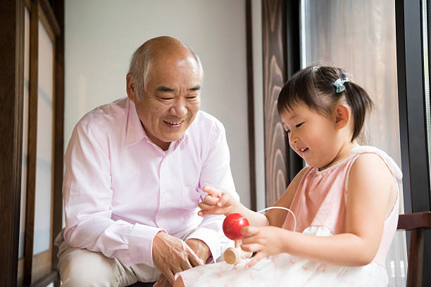 дедушка смотрит, как внучка играет с традиционной японской игрой - japanese culture japanese ethnicity japan toy стоковые фото и изображения