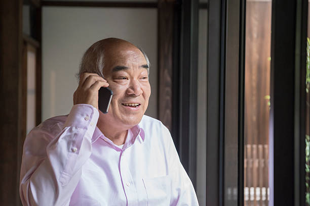 istock Surprised Japanese man on mobile phone smiling 598137946