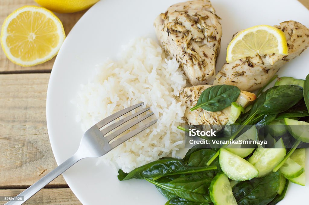Baked chichen breasts with lemon, white rice and green spinach Baked chicken breasts with lemon, white rice and green spinach and cucumber salad Rice - Cereal Plant Stock Photo